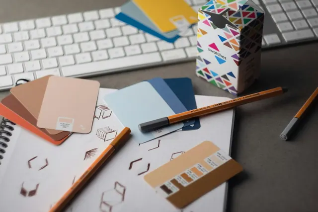 a desk with a keyboard, pencils, and various color samples Swatchos color swatch cards with CMYK and RGB hex values showing being used by a graphic designer on a graphic designer's. The practical 2027 guide to marketing funnels